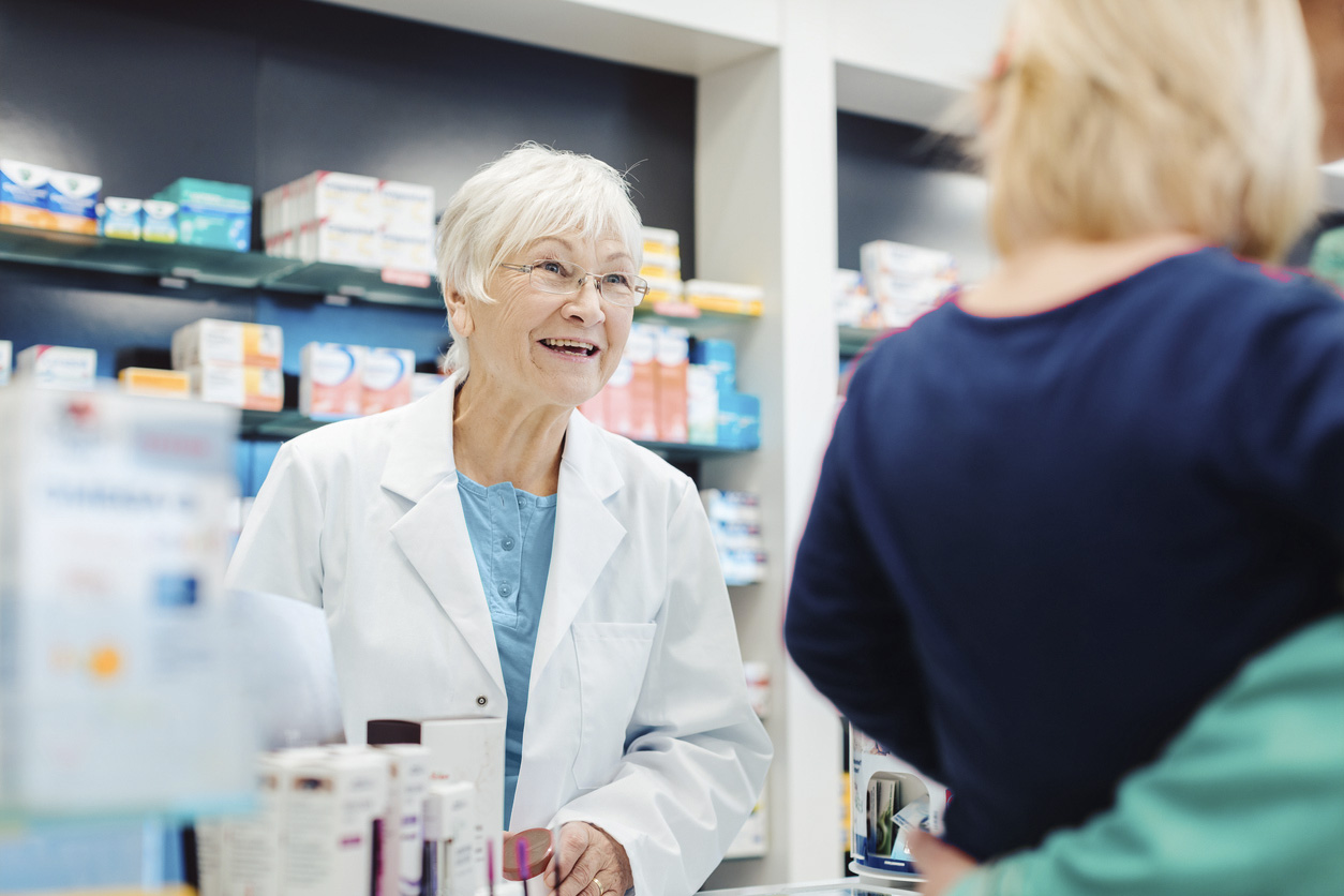 Apothekerin unterhält sich hinter der Theke mit einer anderen Person