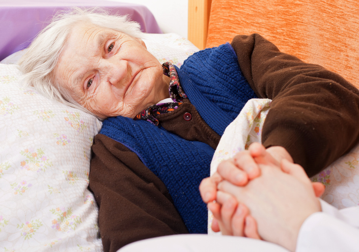 Alte Frau im Bett, der die Hand gehalten wird