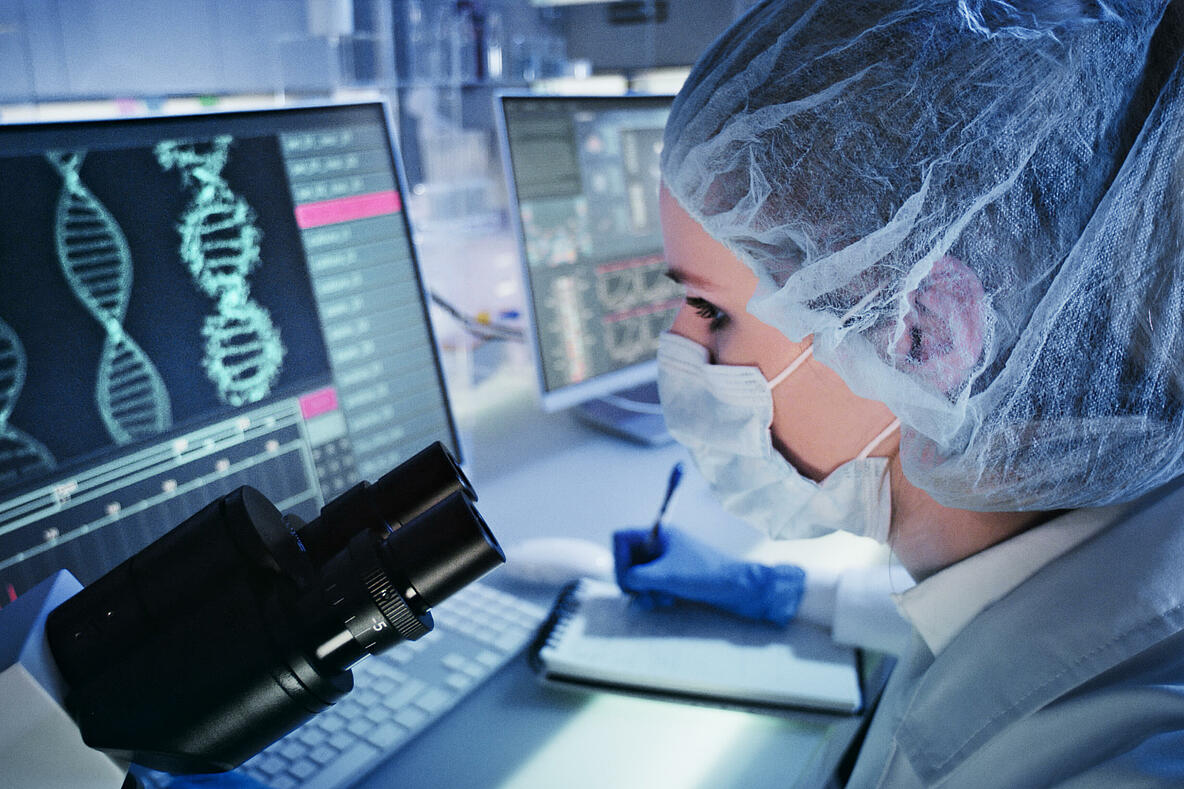 Frau im Labor am Bildschirm mit DNA-Helix