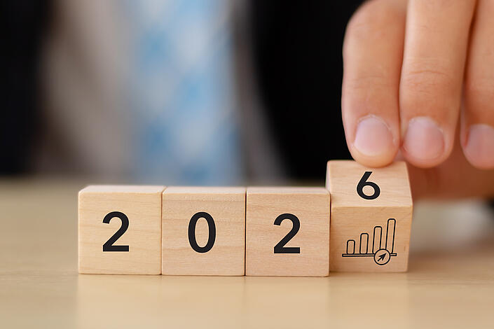 Mann dreht Würfel um, so dass 2026 zu sehen ist