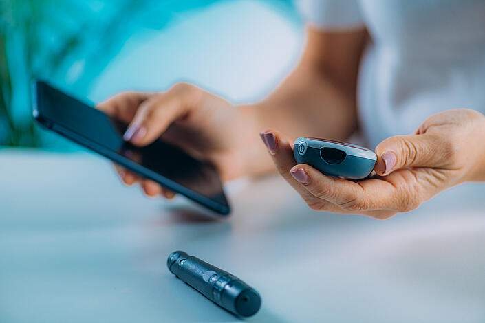 Frau mit Blutzuckertest und Smartphone