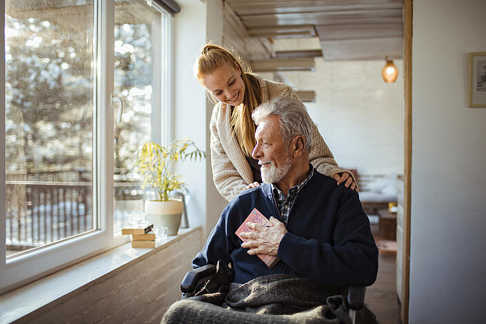 Älterer pflegebedürftiger Mann wird von junger Angehörigen betreut.