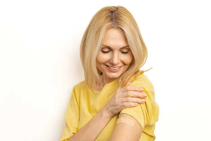 Frau zeigt nach Impfung ihren Arm