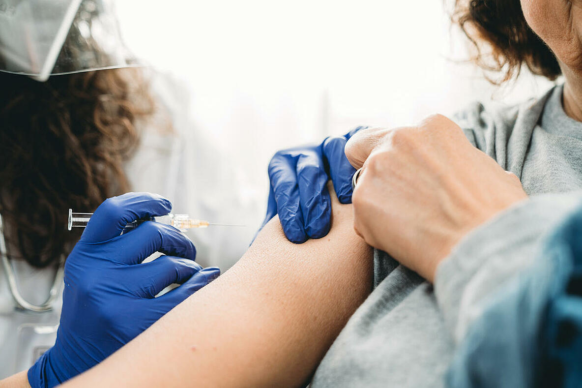 Eine Spritze wird zur Impfung am Oberarm angesetzt