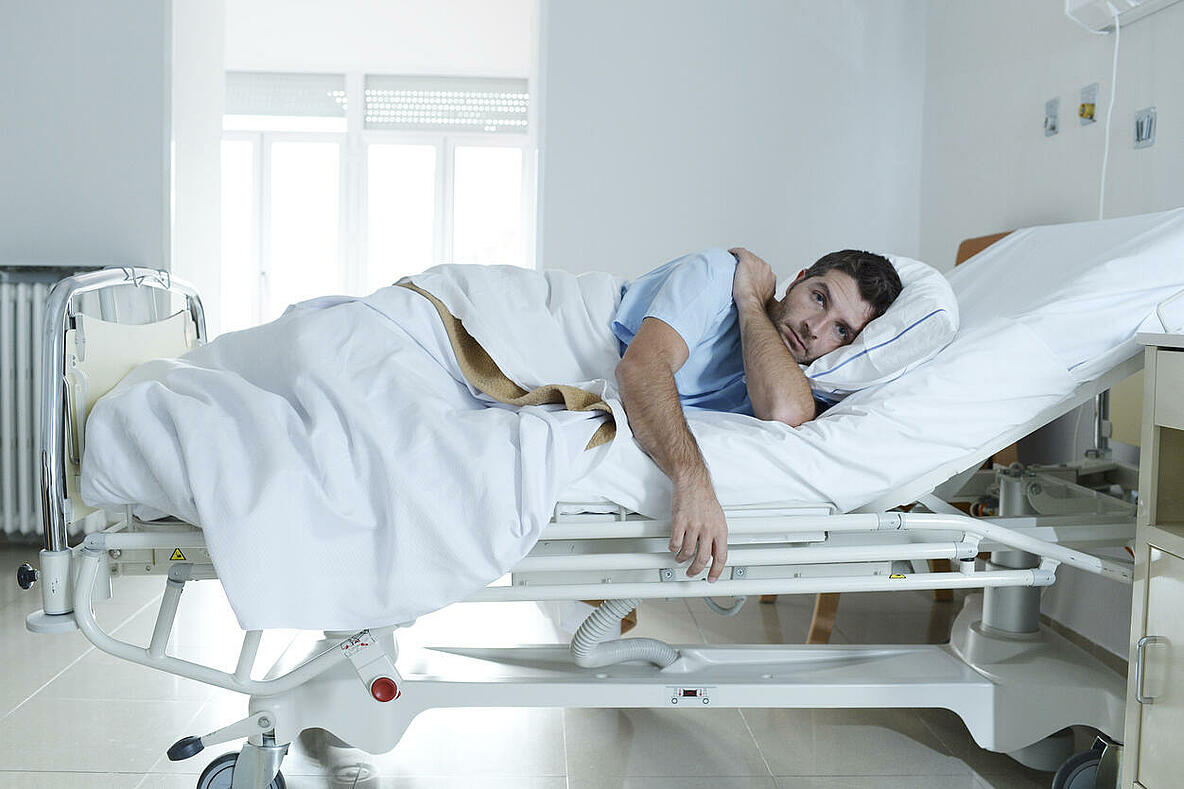 Mann liegt im Krankenhausbett