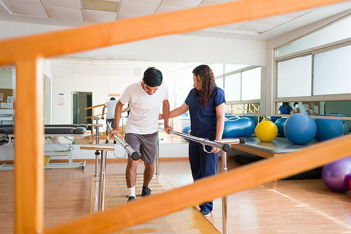 Mann übt das Gehen in einer Physiotherapiepraxis